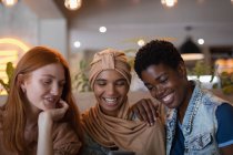 Vorderansicht fröhlicher gemischter Rassen-Freundinnen mit Mobiltelefon im Restaurant — Stockfoto