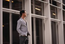 Front view of thoughtful Asian man standing near building — Stock Photo