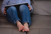 Низька частина маленького хлопчика, використовуючи цифровий планшет, сидячи на дивані вдома — стокове фото