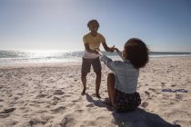 Romántica joven feliz pareja cogida de la mano en la playa en el día soleado - foto de stock