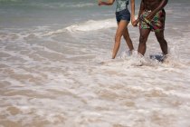 Niedriger Abschnitt des Paares, das Hand in Hand am Strand geht — Stockfoto
