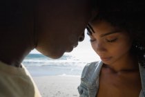 Вид сбоку на счастливую романтическую афроамериканскую пару, стоящую на пляже в солнечный день — стоковое фото