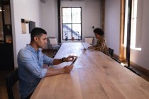 Seitenansicht junger Geschäftsleute mit gemischter Rasse, die am Schreibtisch im modernen Büro an einem digitalen Tablet arbeiten — Stockfoto