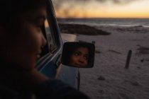 Вид збоку красива жінка думає, сидячи в машині на пляжі — стокове фото