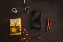 Тестування двигуна мультиметр і мобільний телефон на підлозі в гаражі — стокове фото