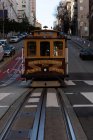 Трамвай движется по тропе через городскую улицу в солнечный день — стоковое фото