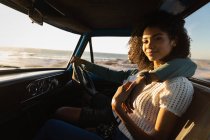 Seitenansicht eines romantischen jungen afrikanisch-amerikanischen Paares, das sich an einem sonnigen Tag im Auto entspannt — Stockfoto