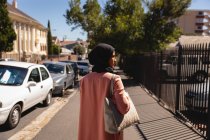 Вид ззаду вдумлива змішана жінка, що стоїть на вулиці в сонячний день — стокове фото