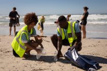Front view of multi ethnic volunteers cleaning beach on a sunny day — Stock Photo