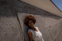 Retrato de jovem muito mista mulher de raça encostada contra a parede na praia em um dia ensolarado — Fotografia de Stock