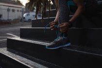 Coupe basse de femme en forme attachant ses lacets dans les escaliers de la ville — Photo de stock