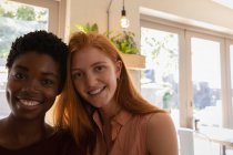 Retrato de jóvenes amigas de raza mixta sonriendo en un café - foto de stock