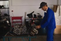 Vue latérale du moteur de réparation de mécanicien de vélo caucasien dans le garage — Photo de stock