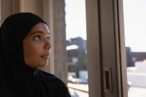 Vue latérale d'une jeune femme réfléchie dans le hijab se détendre dans un café — Photo de stock