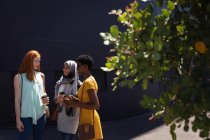 Вид спереду на молоду змішану расу подруги-жінки взаємодіють один з одним на вулиці міста в сонячний день — стокове фото