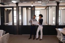 Frontansicht junger Geschäftsleute mit gemischter Rasse, die sich untereinander diskutieren und den Entwurf eines neuen Büros betrachten — Stockfoto