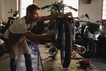Бічний вид цілеспрямованої Кавказького велосипеда механік ремонту велосипеда в гаражі — стокове фото