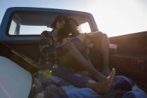 Vorderansicht eines romantischen Paares, das an einem sonnigen Tag im Auto am Strand sitzt — Stockfoto