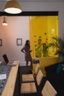 Вид спереду уважного Різні бізнесмени обговорюють над липкими нотами на скляній стіні в офісі — стокове фото