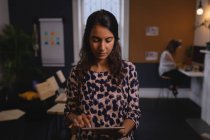 Frontansicht einer jungen schönen weiblichen Führungskraft mit gemischter Rasse, die im Büro am digitalen Tablet arbeitet — Stockfoto