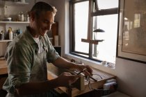Vue latérale du charpentier caucasien mature heureux en utilisant le téléphone mobile dans l'atelier — Photo de stock