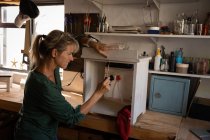 Vue latérale de l'armoire de fixation de charpentier féminin caucasien dans l'atelier — Photo de stock