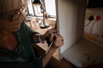 Vista lateral del gabinete de marcado de carpintero femenino caucásico maduro con lápiz en el taller - foto de stock