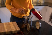Partie médiane de la femme préparant le café dans la cuisine à la maison — Photo de stock
