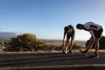 Side view of Caucasian father and son doing stretching exercise on road in the morning — Stock Photo