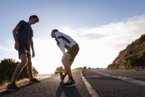 Низкий угол обзора отца и сына кавказца, делающего упражнения на растяжку на дороге утром — стоковое фото