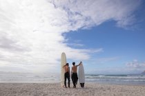 Visão traseira do pai e do filho caucasianos de pé com prancha de surf na praia — Fotografia de Stock