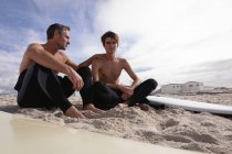 Vista posteriore di padre e figlio caucasico con tavola da surf interagiscono tra loro — Foto stock
