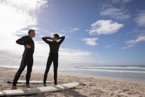 Front view of Caucasian father and son wearing wet suit at beach on a sunny day — Stock Photo