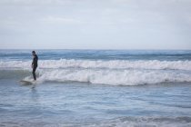 Front view of carefree Caucasian man with surfboard surfing in the sea — Stock Photo
