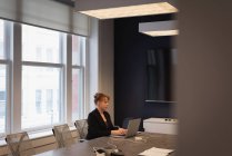 Vista lateral de la mujer de negocios caucásica usando portátil en la sala de conferencias en la oficina - foto de stock