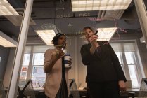 Низкий угол обзора различных бизнес-женщин, планирующих на стеклянной стене в конференц-зале в офисе — стоковое фото