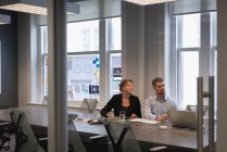 Frontansicht zweier kaukasischer Geschäftsleute, die in einem Konferenzraum im Büro zuhören — Stockfoto