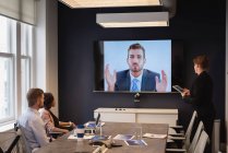 Vista trasera de diversos ejecutivos de negocios que realizan videoconferencias en reuniones de negocios en la oficina - foto de stock