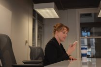 Vista laterale della donna d'affari caucasica che parla al telefono cellulare in sala conferenze in ufficio — Foto stock