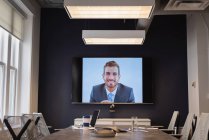 Vista frontal do empresário caucasiano em videochamada à espera de colegas na sala de conferências no escritório — Fotografia de Stock
