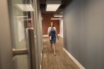 Vista frontale della donna d'affari caucasica che cammina nel corridoio dell'ufficio — Foto stock