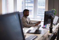 Vista lateral do empresário afro-americano olhando gráfico no escritório — Fotografia de Stock