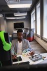Vue de face du créateur de mode homme afro-américain en utilisant une tablette graphique tout en regardant la couleur swatch — Photo de stock