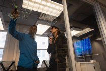 Tiefansicht eines afrikanisch-amerikanischen Geschäftsmannes, der seinem kaukasischen Kollegen ein Wachstumshoroskop an einer Glaswand im Büro zeigt — Stockfoto