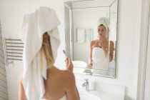 Задумчивая красивая женщина, стоящая перед зеркалом, держа зубную щетку — стоковое фото