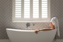 Thoughtful woman sitting in the bathtub in bathroom at home — Stock Photo