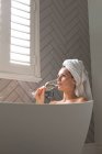 Bella donna che ha champagne nella vasca da bagno a casa — Foto stock