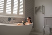 Женщина читала книгу в ванне в ванной — стоковое фото