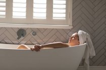 Beautiful woman relaxing in the bathtub in bathroom — Stock Photo