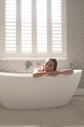 Женщина облокотилась на ванну в ванной дома — стоковое фото